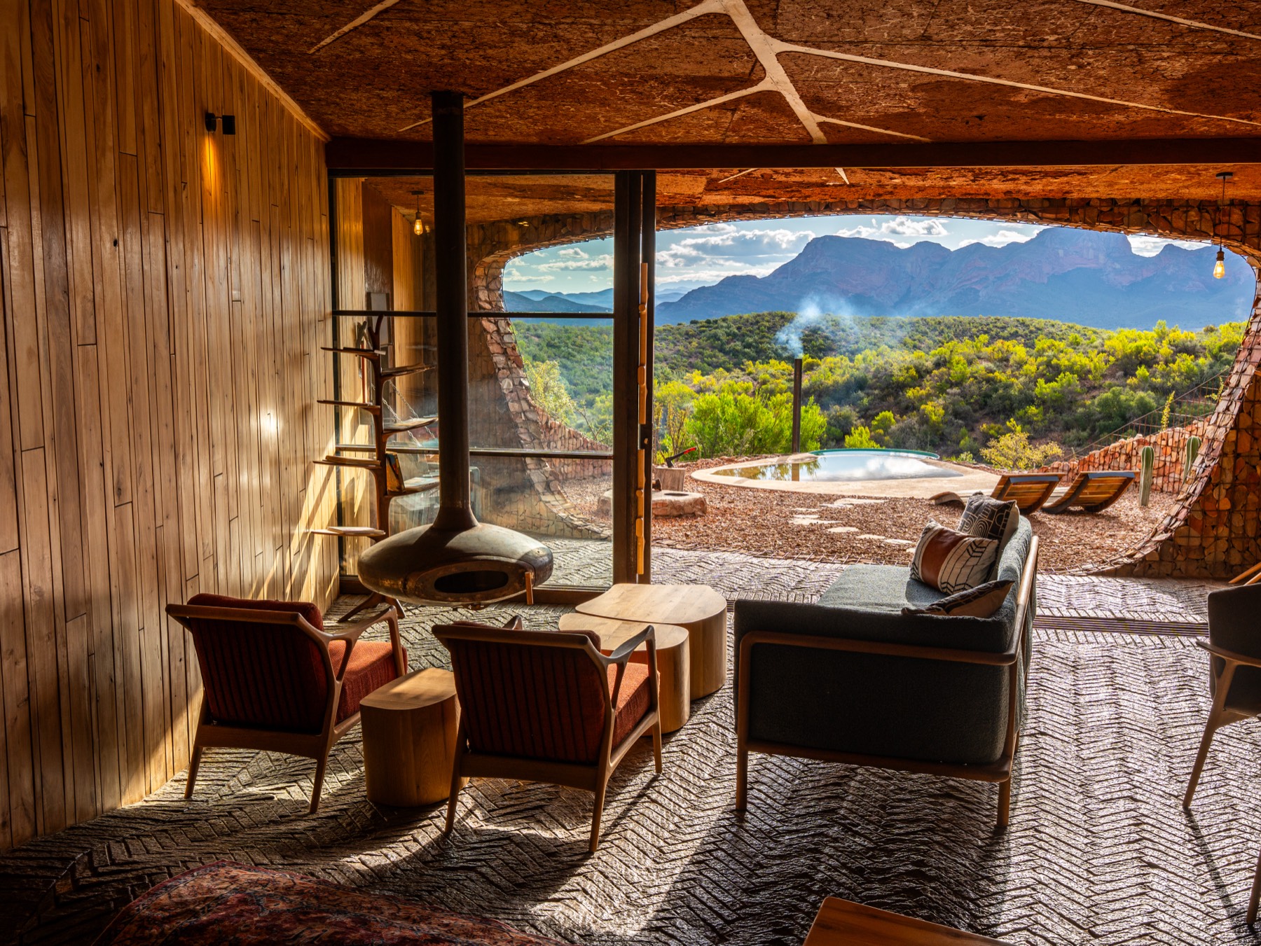Open-plan lodge lounge with fireplace and pool view — hospitality photography